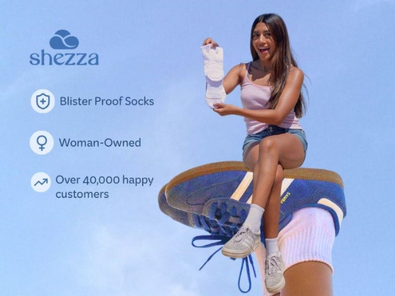 Woman holding a blisters, sitting on a shoe with 'shezza' branding. Best padded sock to break in stiff shoes like Adidas Samabs, Mary Janes, Loafers and Doc Marten Boots